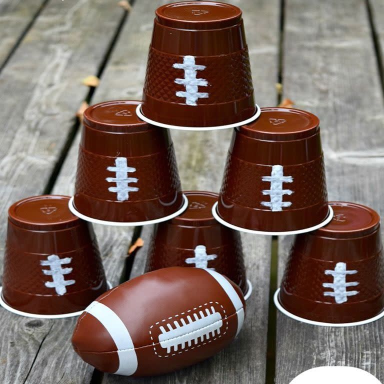 <p>Play a game of football knockdown with small brown cups and a soft football. Use a white paint pen to draw laces on your cups before stacking them upside down. Take turns knocking them down with the football!</p><p><a href="https://kidfriendlythingstodo.com/football-watch-party-football-themed-drink-cozies-and-more/" rel="nofollow noopener" target="_blank" data-ylk="slk:Get the tutorial at Kid Friendly Things To Do »;elm:context_link;itc:0;sec:content-canvas" class="link "><em>Get the tutorial at Kid Friendly Things To Do »</em></a> <br></p>