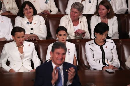 Democratic women of the U.S. House of Representatives, including Rep. Alexandria Ocasio-Cortez (D-NY) (C), remain in their seats as Senator Joe Manchin (D-WV) stands and applauds in front of them as President Trump delivers his second State of the Union address. REUTERS/Jonathan Ernst