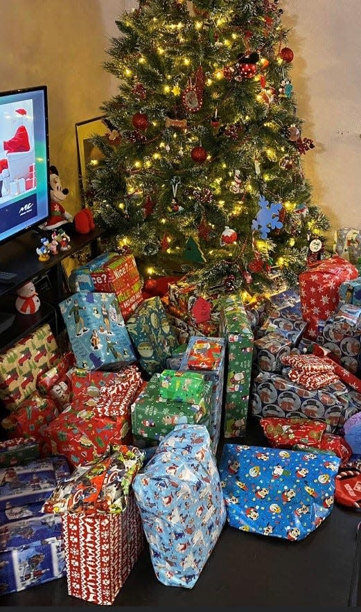 This family Christmas tree is surrounded by gifts parents  purchased for their several children last year with Give a Christmas gift certifcates