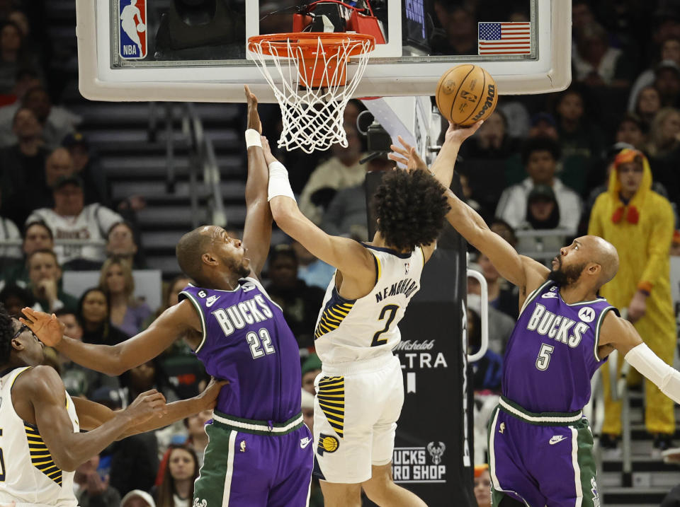 Indiana Pacers guard Andrew Nembhard (2) drives between Milwaukee Bucks forward Khris Middleton (22) and Milwaukee Bucks guard Jevon Carter (5) during the second half of an NBA basketball game Thursday, March 16, 2023, in Milwaukee. (AP Photo/Jeffrey Phelps)