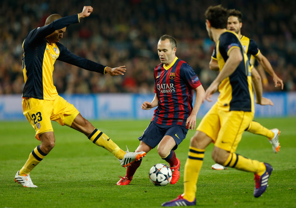 Barcelona's Andres Iniesta, center, challenges the Atletico defense during a first leg quarterfinal Champions League soccer match between Barcelona and Atletico Madrid at the Camp Nou stadium in Barcelona, Spain, Tuesday April 1, 2014. (AP Photo/Emilio Morenatti)