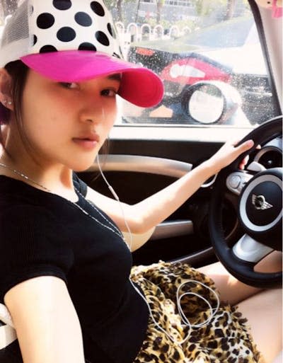 Woman with cap sits in a car.