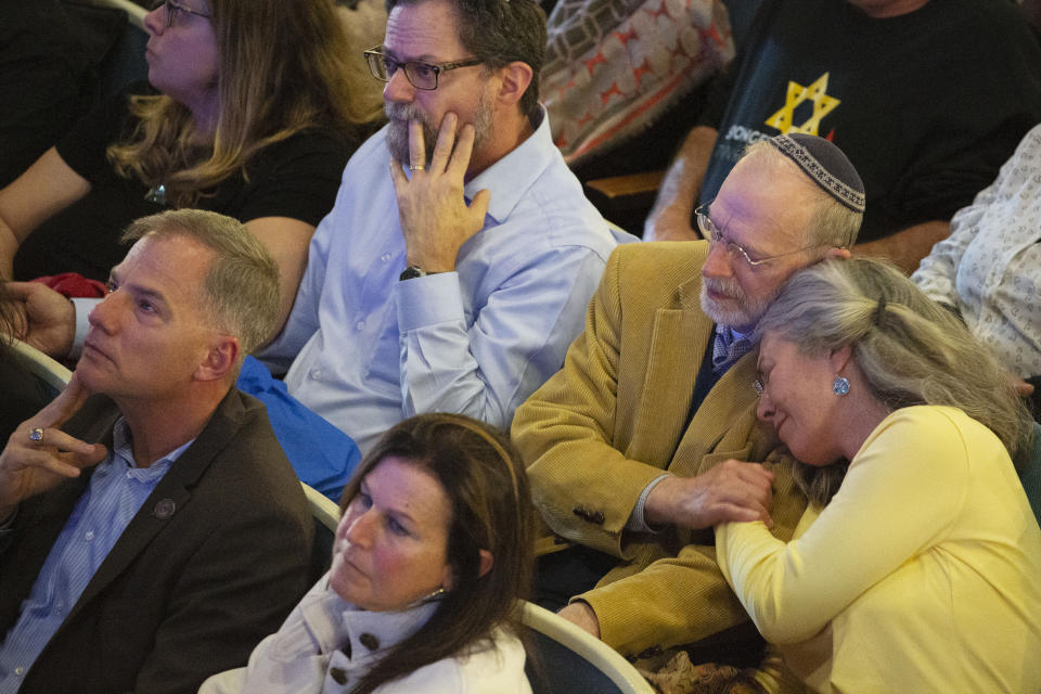 Daniel Leger, second from right, and his wife, Ellen Leger, embrace during the one-year commemoration of the Tree of Life synagogue attack, at Soldiers & Sailors Memorial Hall and Museum, Sunday, Oct. 27, 2019, in Pittsburgh. Dan Leger was seriously wounded during the attack. (AP Photo/Rebecca Droke)