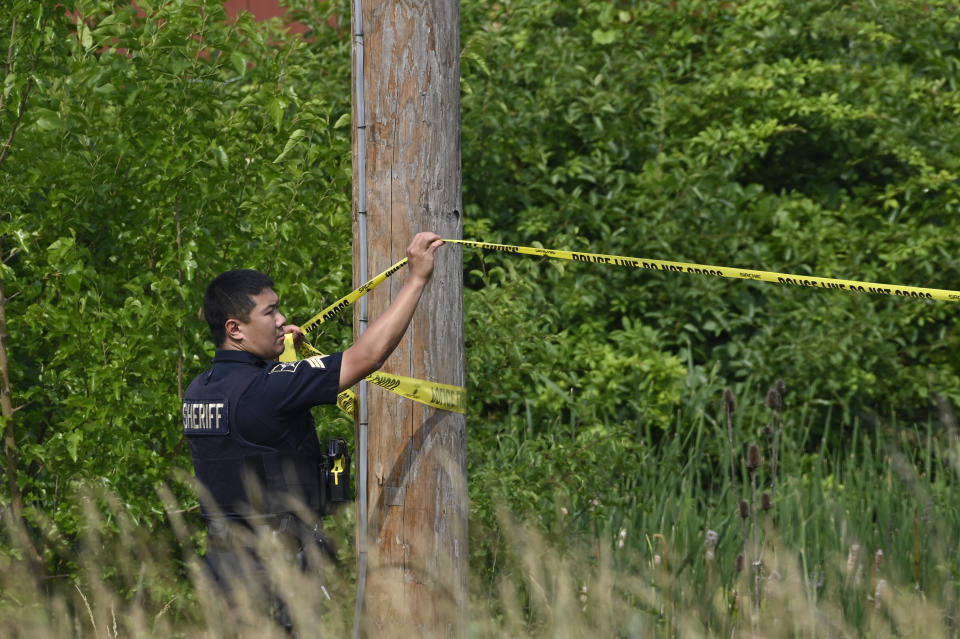 A police officer hangs caution tape at the scene of an overnight mass shooting at a strip mall in Willowbrook, Ill., Sunday, June 18, 2023. (AP Photo/Matt Marton)