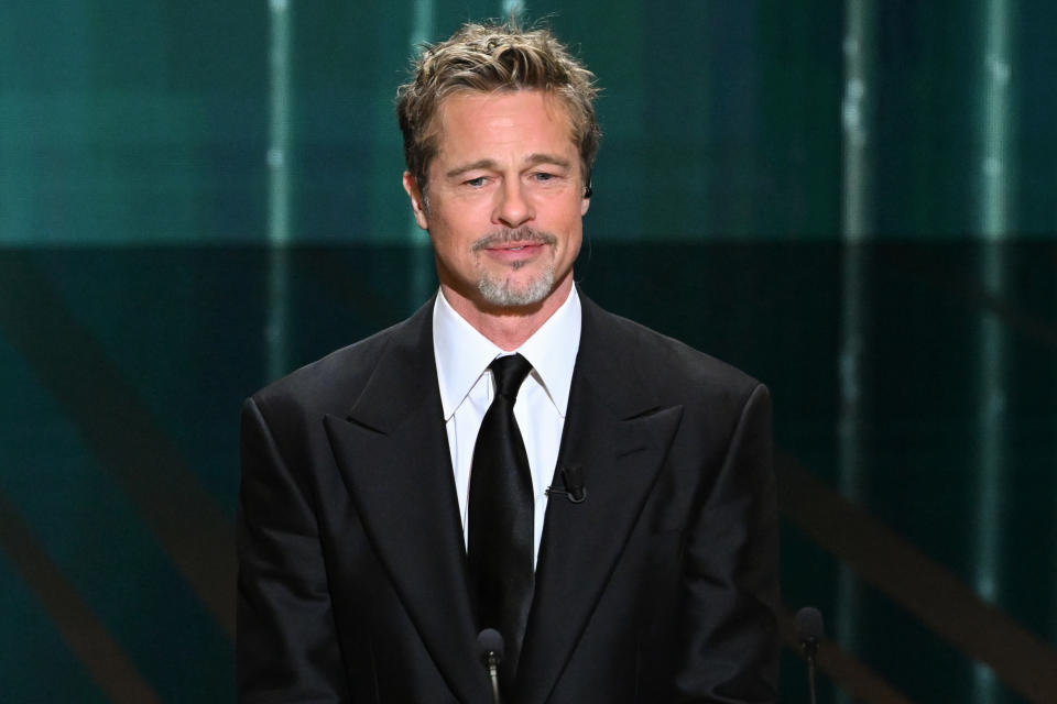 Close-up of Brad in a suit and tie onstage at a microphone