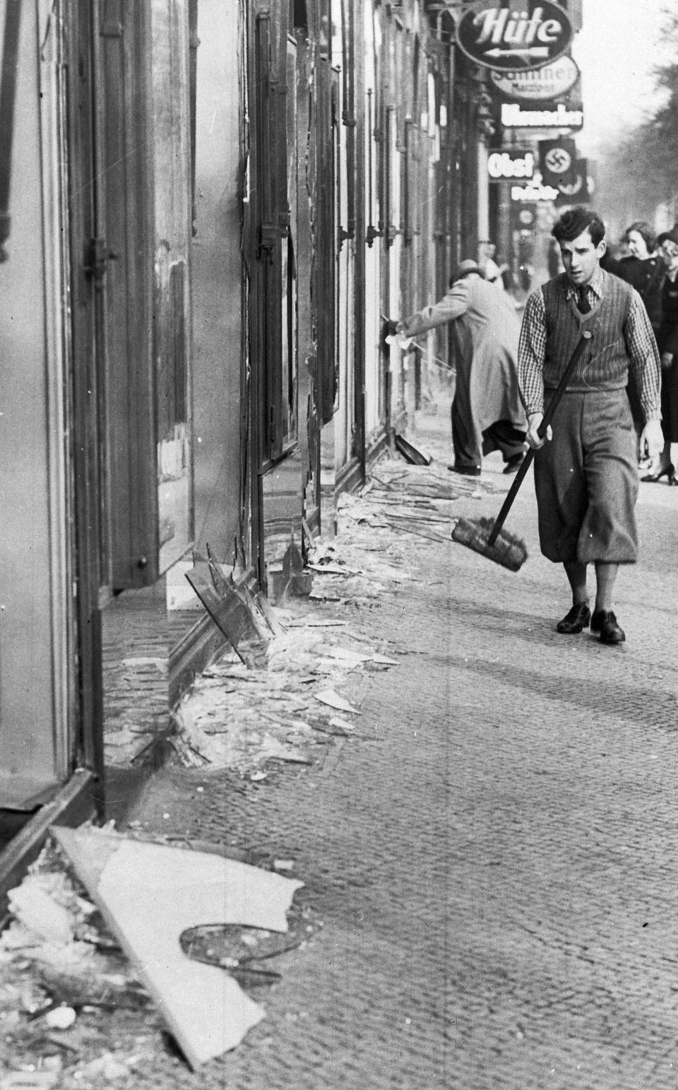 FILE - In this Nov. 10, 1938 file picture, a youth with a broom prepares to clear up the broken window glass from a Jewish shop in Berlin, the day after the "Kristallnacht" rampage when Nazis set fire to hundreds of synagogues, looted thousands of Jewish businesses and attacked Jews in Germany and Austria. Holocaust survivors from around the world are warning about the reemergence of antisemitism as they commemorated Wednesday, Nov. 9, 2022, the 84th anniversary of the Kristallnacht or the "Night of Broken Glass", when Nazis terrorized Jews throughout Germany and Austria. (AP Photo/File)