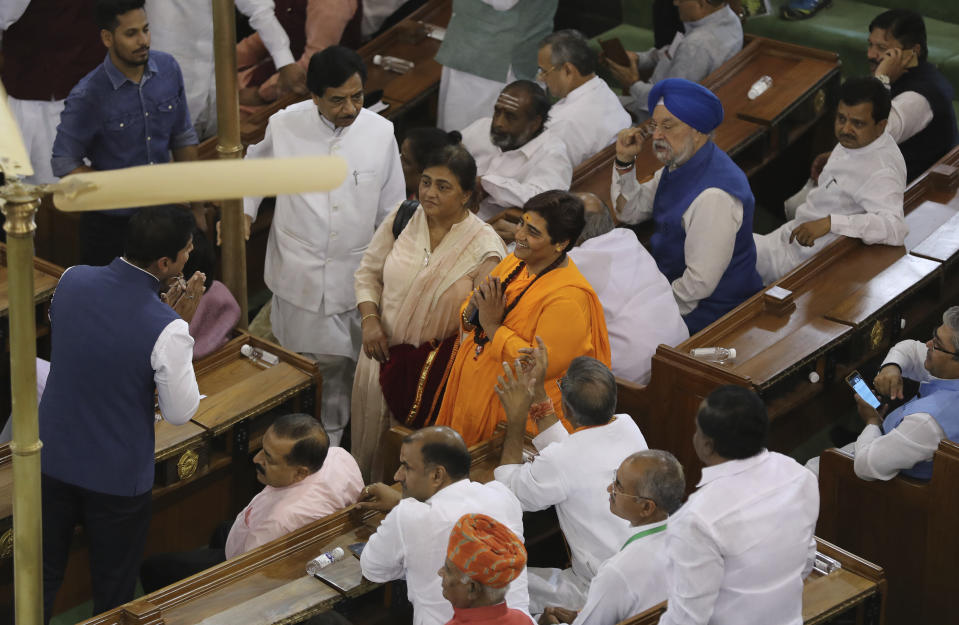 Newly elected lawmakers Pragya Singh Thakur, center in orange dress, greets other lawmakers on her arrival at Bharatiya Janata Party parliamentary and their alliance meeting to elect Narendra Modi as their leader in New Delhi, India, Saturday, May 25, 2019. Shah announced Modi's name as the leader of the National Democratic Alliance in a meeting of the lawmakers in the Central Hall of Parliament in New Delhi, paving the way for Modi's second five-year term as prime minister after a thunderous victory in national elections. On the left, is the huge portrait of India's first prime minister Jawaharlal Nehru. (AP Photo/Manish Swarup)