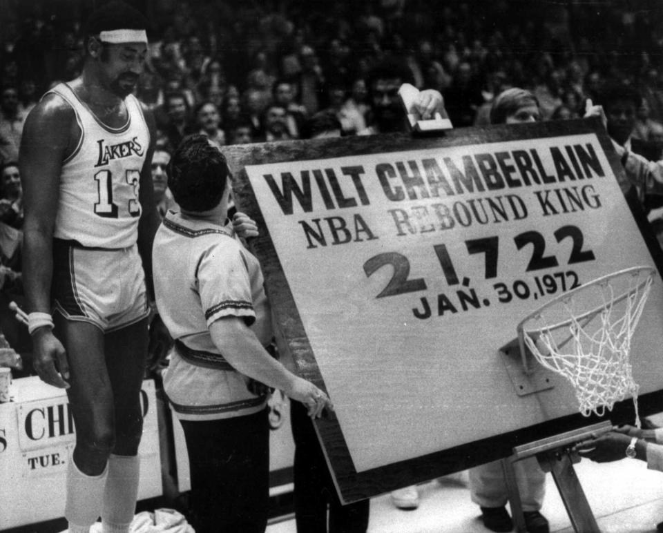 Los Angeles Lakers' Wilt Chamberlain, left, stands beside a backboard and hoop trophy that was presented to him after he became the all-time leading rebounder in NBA history, in Los Angeles, Jan. 31, 1972.  (AP Photo)