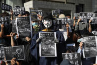 A protester wears a Guy Fawke mask as he joins others with signs against police brutality at the University of Science and Technology in Hong Kong on Friday, Nov. 8, 2019. Chow Tsz-Lok, a student from the University who fell off a parking garage after police fired tear gas during clashes with anti-government protesters died Friday, in a rare fatality after five months of unrest that intensified anger in the semi-autonomous Chinese territory. (AP Photo/Kin Cheung)