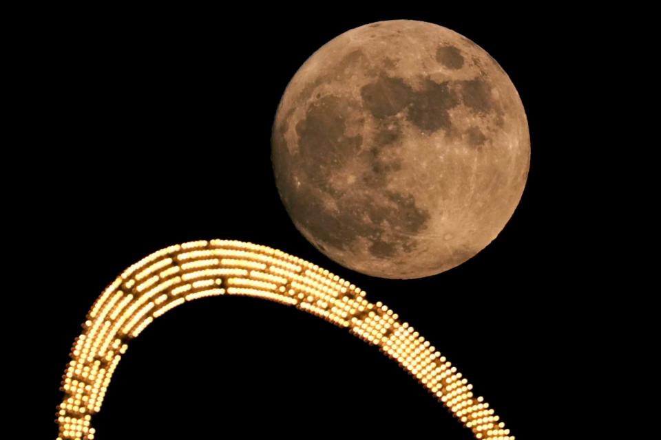 The full moon rises beyond a sign on top an apartment building in Kansas City (AP)