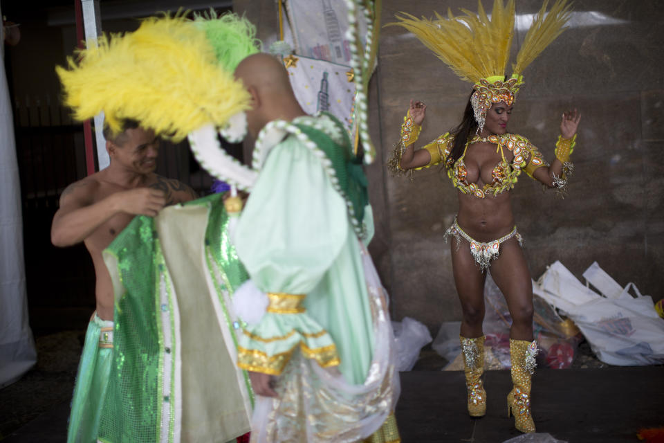 In this photo taken Saturday, Feb. 2, 2013, samba dancer Diana Prado, right, warms up for a carnival parade at central station in Rio de Janeiro, Brazil. A call center supervisor by day the 27-year-old's double life is split down the middle between the glitz and glam, feathers and body paint of Carnival and the workaday office reality of head-sets and cubicles. Rio de Janeiro samba school dancers are the star attractions of the world's most iconic Carnival celebrations. But they're not on the payroll of the samba groups they represent - and many have to work decidedly unglamorous jobs, serving as maids or secretaries to make ends meet. (AP Photo/Felipe Dana)