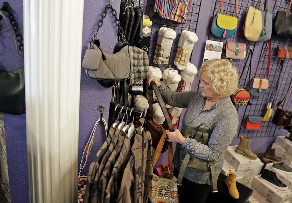 Employee Terri Schultz hangs purses on display at Lillian's of Appleton on Tuesday, November 22, 2022, Appleton, Wis.