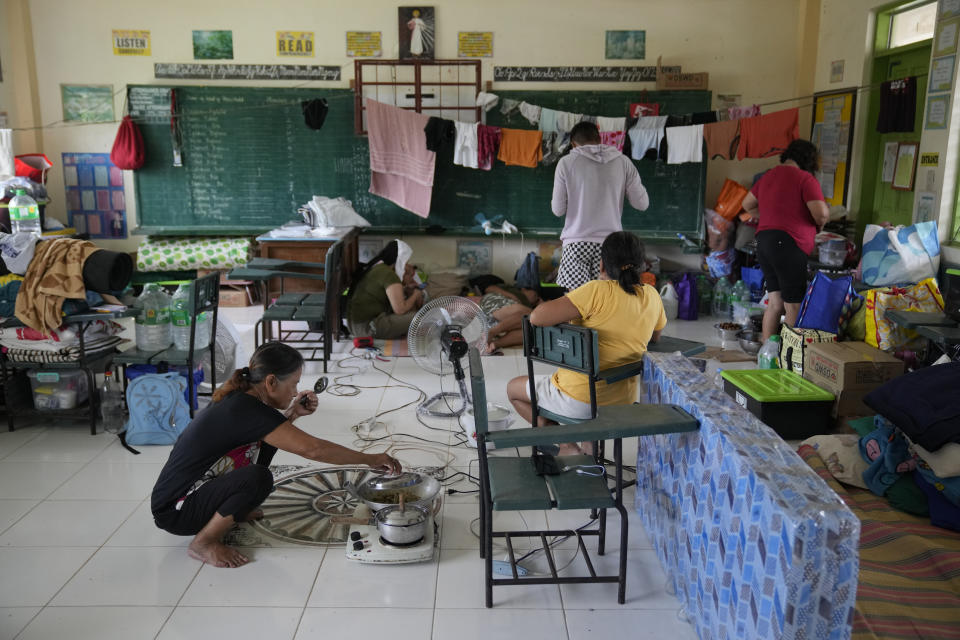 An evacuee prepares a meal at an evacuation center at Malilipot town, Albay province, northeastern Philippines, Thursday, June 15, 2023. Thousands of residents have left the mostly poor farming communities within a 6-kilometer (3.7-mile) radius of Mayon's crater in forced evacuations since volcanic activity spiked last week. (AP Photo/Aaron Favila)