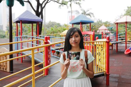 Chau Ho-oi, who was born six months before the Hong Kong's handover to Chinese rule in 1997, poses with her childhood photo which taken at the same spot in 1999, at Kowloon Park in Hong Kong, China June 3, 2017. REUTERS/Tyrone Siu