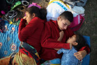 <p>The Zelaya siblings, from El Salvador, Nayeli, right, Anderson, center, and Daniela, huddle together on a soccer field, at the sports club where Central American migrants traveling with the annual “Stations of the Cross” caravan are camped out, in Matias Romero, Oaxaca State, Mexico on April 4, 2018. The children’s father Elmer Zelaya, 38, said the family is awaiting temporary transit visas that would allow them to continue to the U.S. border, where they hope to request asylum and join relatives in New York. (Photo: Felix Marquez/AP) </p>