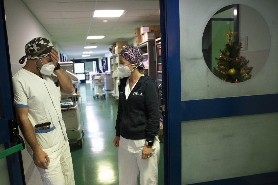 Nurses Glenda Grossi, right, talks with her husband Maurizio di Giacobbe at the end of her shift in the COVID-19 ICU of the Tor Vergata Polyclinic Hospital, Sunday, Dec. 13, 2020. The coronavirus pandemic has posed unprecedented challenges for families around the world managing work and home life with children kept home from school and after-school activities. For the Di Giacobbe family, the juggling is even more complicated since mom and dad are intensive care nurses in the same COVID-19 ward and spend their days tag-teaming shifts, trying to give their patients the level of personal care and attention they would give their own children. (AP Photo/Alessandra Tarantino)