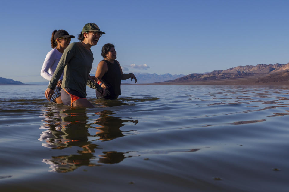 Francesca Gambini, left, Cara Tan, center, and Alejandra Pulido laugh as the return to shore after trying to cross on a temporary lake on foot in Death Valley on Thursday, Feb. 23, 2024, in Death Valley National Park, Calif. A series of storms have brought more than double the parks annual rainfall in the past six months. (AP Photo/Ty ONeil)