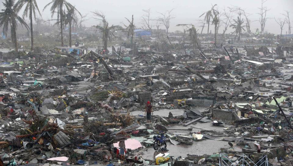 RNPS - PICTURES OF THE YEAR 2013 - Survivors stand among debris and ruins of houses destroyed after Super Typhoon Haiyan battered Tacloban city in central Philippines November 10, 2013. Haiyan, one of the most powerful storms ever recorded killed at least 10,000 people in the central Philippines province of Leyte, a senior police official said, with coastal towns and the regional capital devastated by huge waves. Super typhoon Haiyan destroyed about 70 to 80 percent of the area in its path as it tore through the province on Friday, said chief superintendent Elmer Soria, a regional police director. REUTERS/Erik De Castro (PHILIPPINES - Tags: DISASTER ENVIRONMENT TPX)