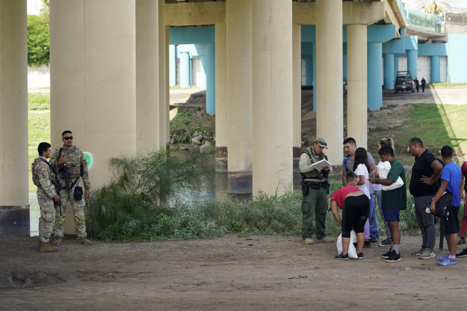 Migrants wait to be processed by the Border Patrol after illegally crossing the Rio Grande river from Mexico into the U.S. at Eagle Pass, Texas, Friday, Aug. 26, 2022. The area has become entangled in a turf war between the Biden administration and Texas Gov. Greg Abbott over how to police the U.S. border with Mexico. (AP Photo/Eric Gay)