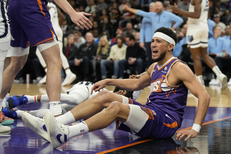 Phoenix Suns guard Devin Booker, right, reacts after getting called for an offensive foul during the first half of an NBA basketball game against the Memphis Grizzlies, Sunday, Jan. 7, 2024, in Phoenix. (AP Photo/Rick Scuteri)