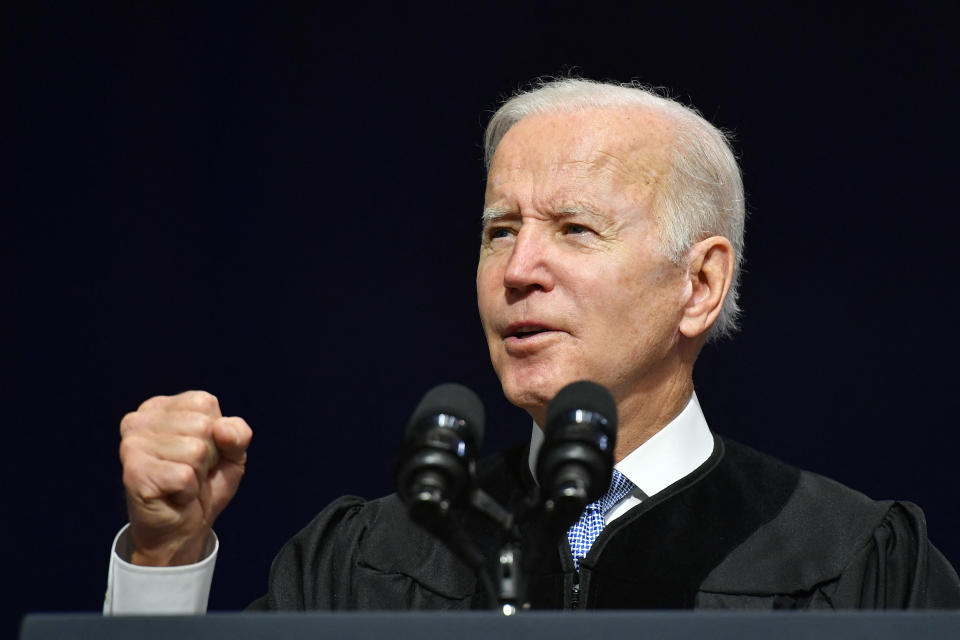 President Biden speaks into microphones at a podium and gestures with his fist.