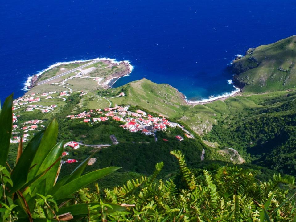 A top-down view of Saba island with the airport in the top left of the picture with the blue ocean in the background.