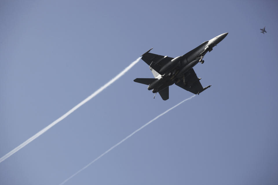 In this Monday, March 20, 2017 photograph, an F-18 fighter jet flies over the USS George H.W. Bush as the vessel travels toward the Strait of Hormuz. The arrival of the nuclear-powered aircraft carrier to the Persian Gulf marks the first such deployment under new U.S. President Donald Trump. (AP Photo/Jon Gambrell)