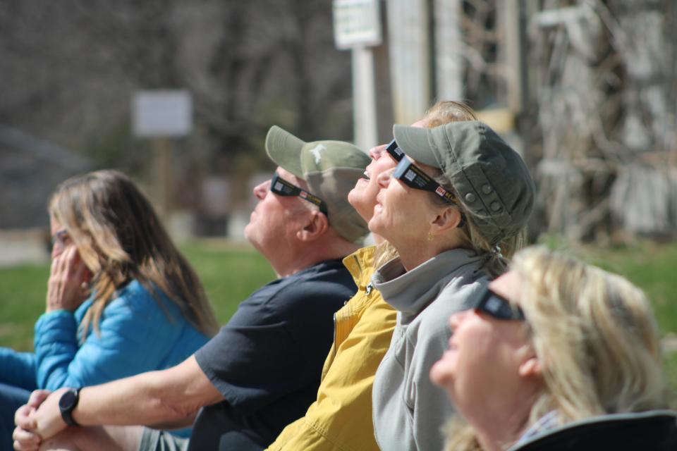 People look up at the solar eclipse on Monday, April 8, at the Raven Hill Discovery Center where intermittent clouds allowed the crowd glimpses of the unique event.