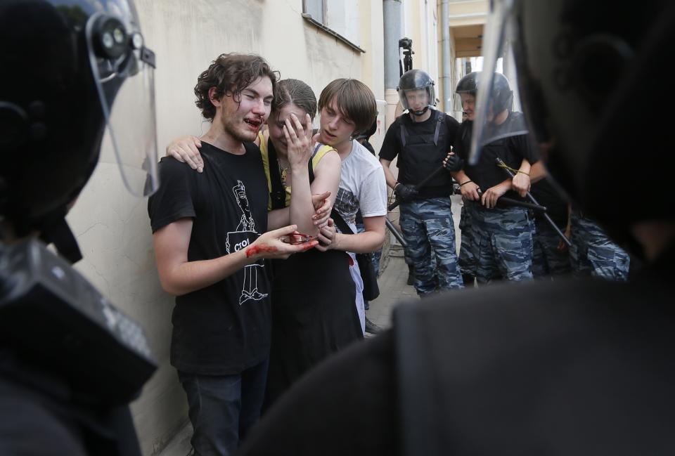 FILE - In this Saturday, June 29, 2013, file photo, riot police guard gay rights activists who were beaten by anti-gay protesters during an authorized gay rights rally in St. Petersburg, Russia. When the Sochi Winter Olympics begin on Friday, Feb. 7, 2014, many will be watching to see whether Russia will enforce its law banning gay “propaganda” among minors if athletes, fans or activists wave rainbow flags or speak out in protest. The message so far has been confusing. (AP Photo/Dmitry Lovetsky, File)