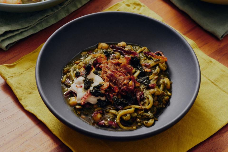 A bowl of soup with noodles, greens and chickpeas