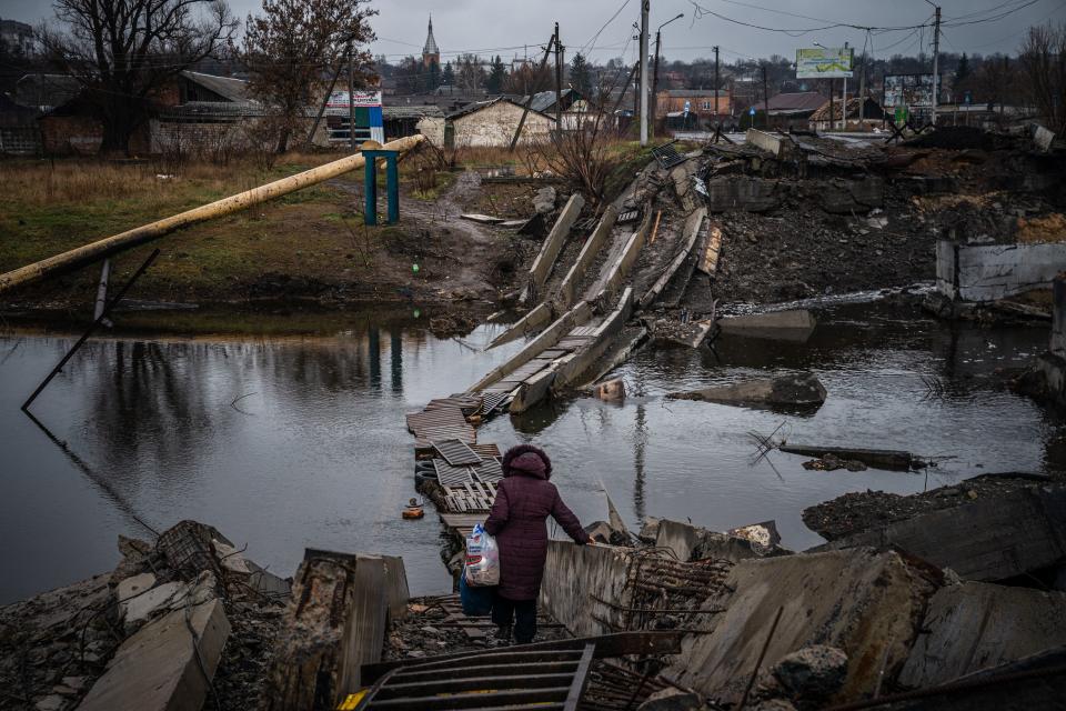 A woman picks her way across a destroyed bridge in Bakhmut, in Donetsk.