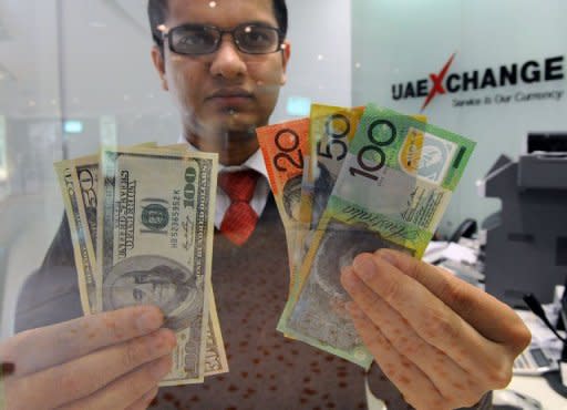 A money changer displays a selection of US dollars (L) and Australian polymer notes (R) in Sydney on May 14, 2012. The Australian dollar dropped below parity with the greenback on Monday for the first time since December as political turmoil in Greece led traders to sell riskier assets