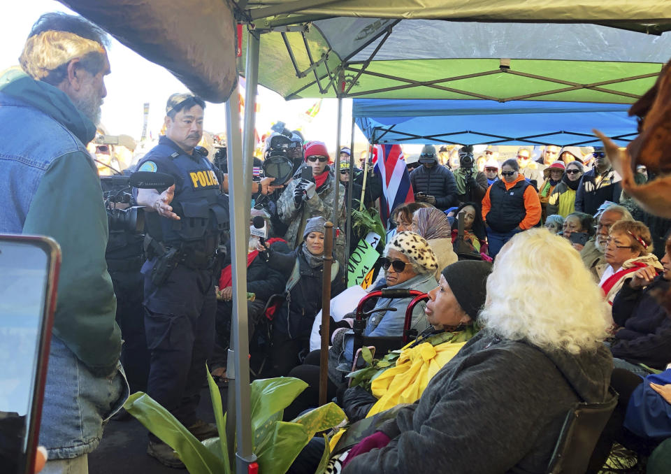 FILE - Officers from the Hawaii Department of Land and Natural Resources prepare to arrest protesters, many of them elderly, who are blocking a road to prevent construction of a giant telescope on a mountain that some Native Hawaiians consider sacred, on Mauna Kea on the Big Island of Hawaii on July 17, 2019. For over 50 years, telescopes have dominated the summit of Mauna Kea, a place sacred to Native Hawaiians and one of the best places in the world to study the night sky. That's now changing with a new state law saying Mauna Kea must be protected for future generations and that science must be balanced with culture and the environment. (Cindy Ellen Russell/Honolulu Star-Advertiser via AP, File)