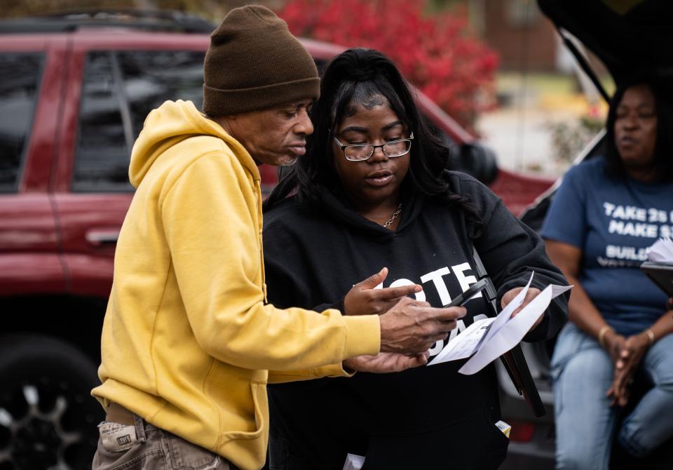 Ebony DeLoach, right, a member of the Ohio Organizing Collaborative, a voting rights organization, talks to a Cincinnati resident, right, about registering to vote before the 2022 midterm elections.