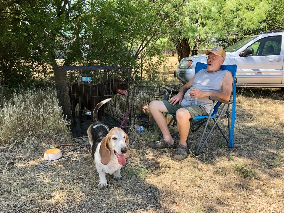 A wildfire southwest of View forced J. B. Merritt and his wife to evacuate with minutes notice Tuesday afternoon. He sat Wednesday morning in the shade of the View Baptist Church parking lot with 12-year-old Bassett Hound Gracie and his other dogs waiting for the OK to survey his burned house.