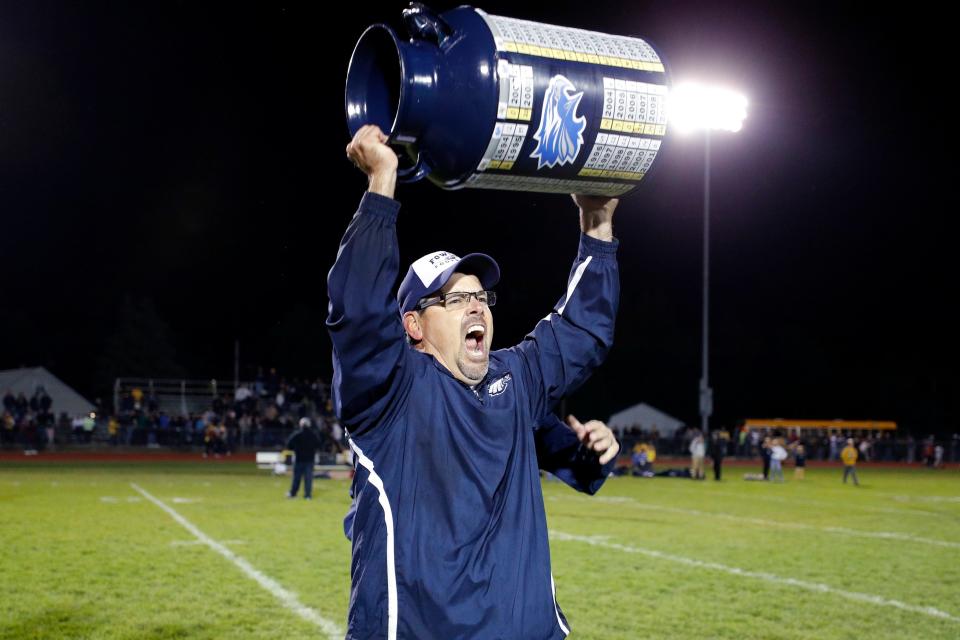 Fowler coach John Spicer raises the game trophy after defeating Pewamo-Westphalia, Friday, Sept. 23, 2022, in Fowler. Fowler won 20-16.