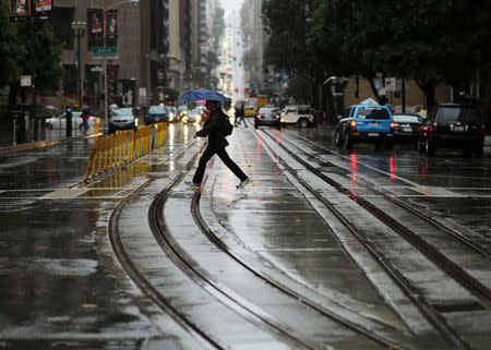 A pedestrian crosses the idle California Street cable car line in San Francisco, California December 11, 2014. REUTERS/Robert Galbraith