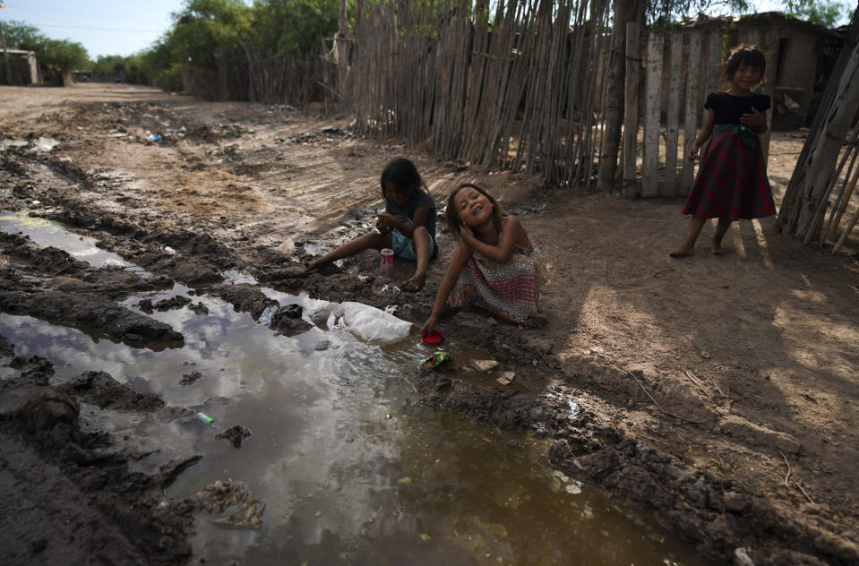 Yaqui Indigenous girls play in water from a leak outside their home in the hometown of slain water-defense leader Tomás Rojo, in Potam, Mexico Tuesday, Sept. 27, 2022. Only those wealthy enough to buy and operate small electric pumps have running water. (AP Photo/Fernando Llano)