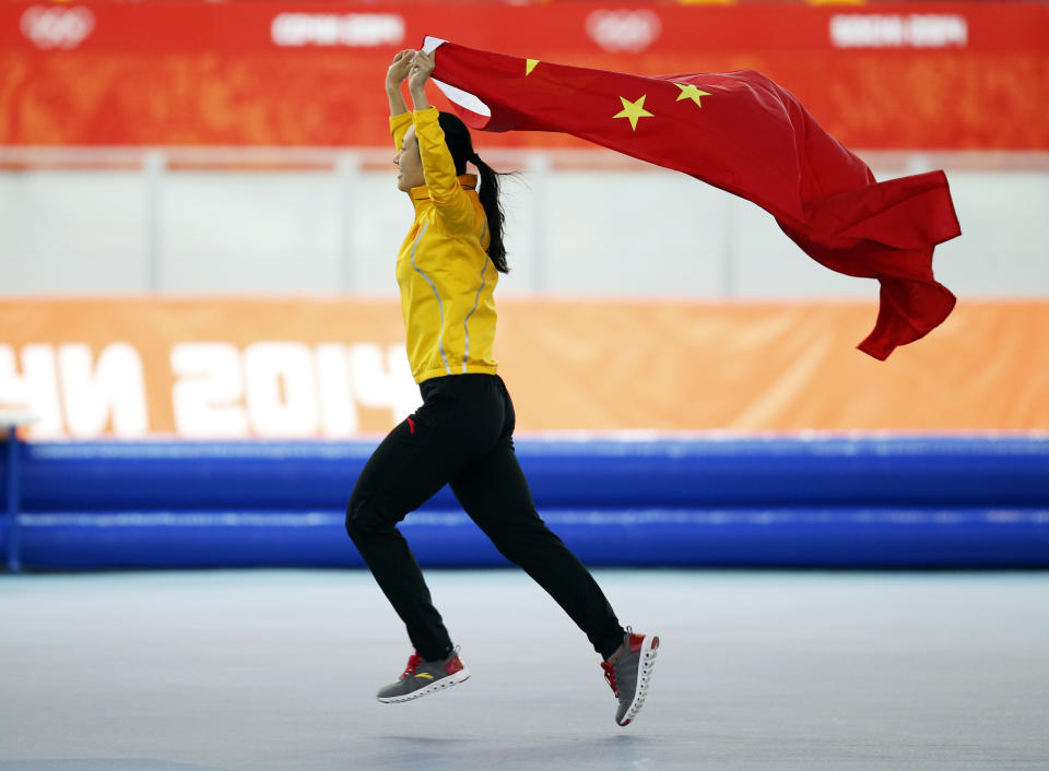 Gold medallist China's Zang Hong holds her national flag and runs in celebration after the women's 1,000-meter speedskating race at the Adler Arena Skating Center during the 2014 Winter Olympics in Sochi, Russia, Thursday, Feb. 13, 2014. (AP Photo/Pavel Golovkin, File)