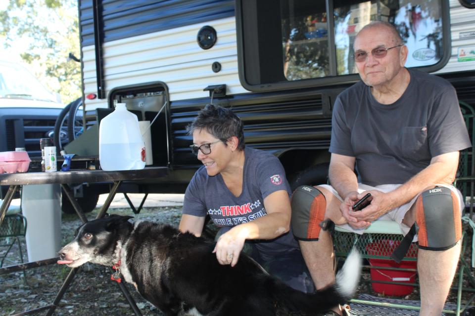 Deborah and John Dee and their dog, Dingo, in front of their camping trailer on Saturday. The trailer is now home after Tropical Storm Ian flooded their house on Devon Street in Port Orange.