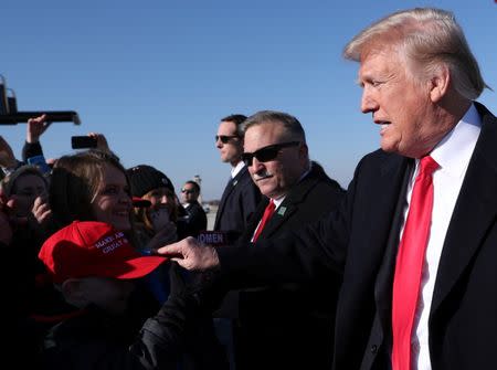 U.S. President Donald Trump grabs the brim of a young boy's "Make America Great Again" cap as he is greeted by supporters waiting for him on the airport tarmac while arriving in Kansas City, Missouri, U.S., December 7, 2018. REUTERS/Jonathan Ernst