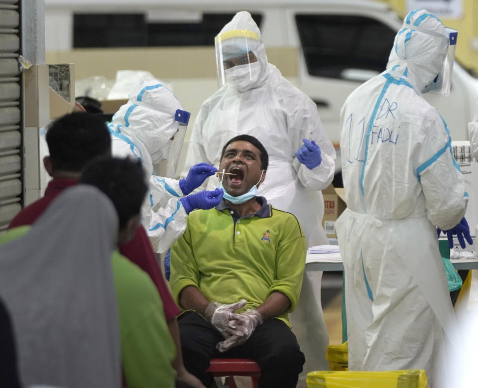 A health worker collects sample for coronavirus testing from a worker at a locked down wet market as one of its traders tested positive for COVID-19 in Petaling Jaya, Malaysia, Tuesday, April 28, 2020. The Malaysian government issued a restricted movement order to the public till April 28, to help curb the spread of the new coronavirus. (AP Photo/Vincent Thian)