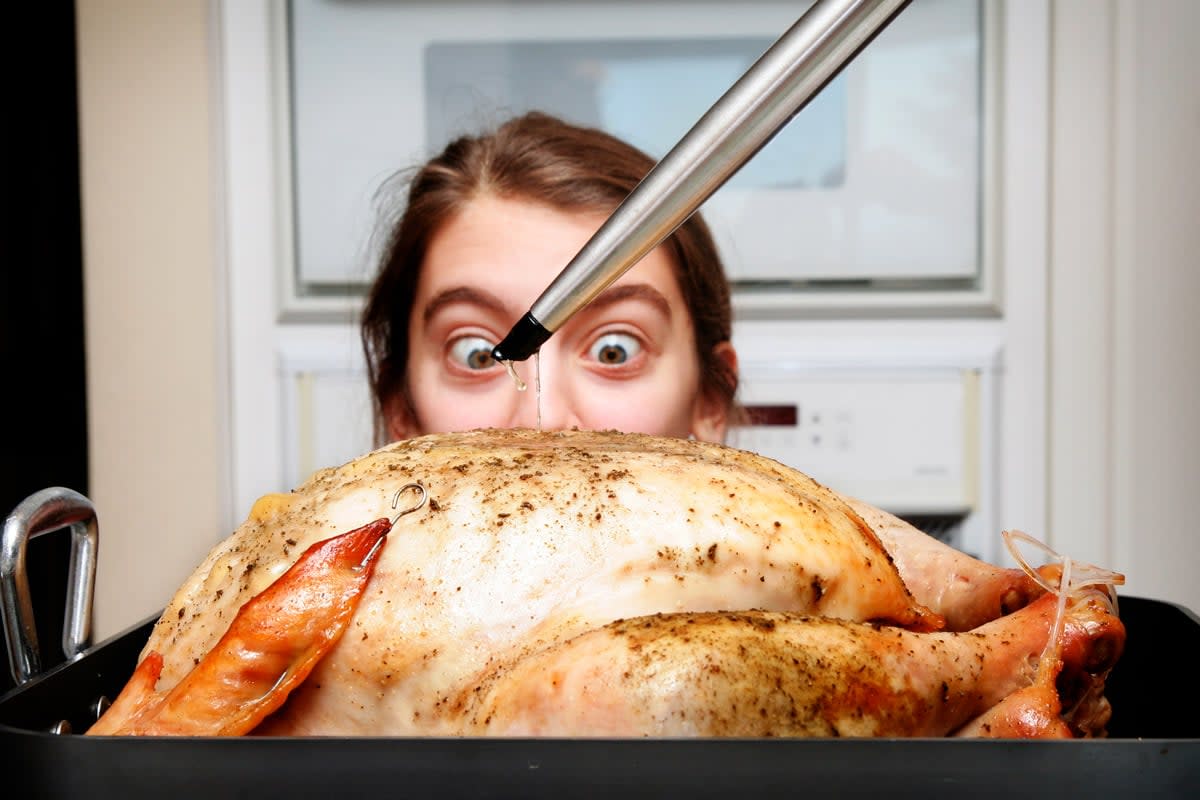 A woman watches as someone cooks the turkey.