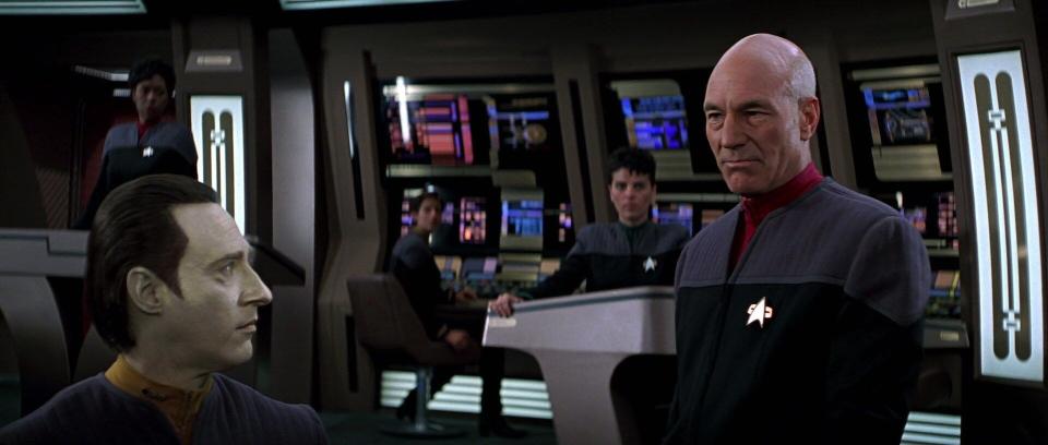 Captain Picard and the crew of the Enterprise-E on the bridge.