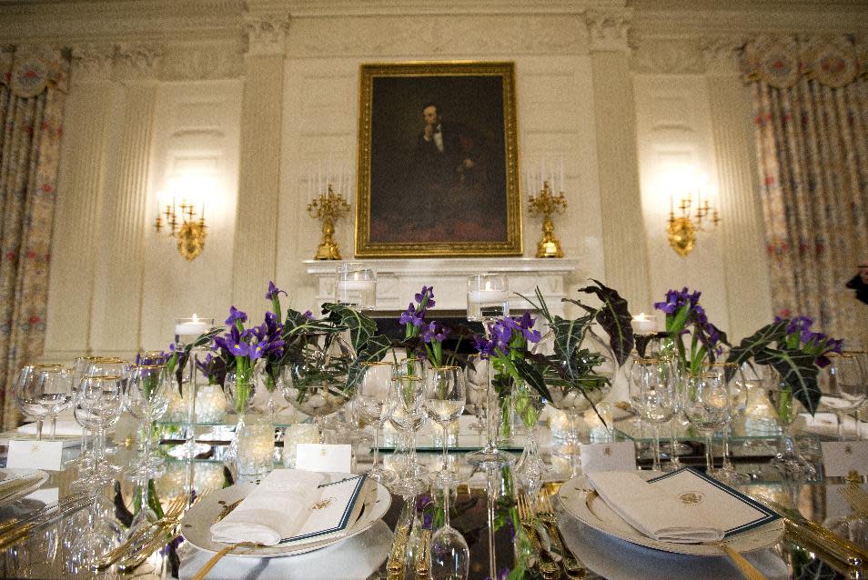 A view of the table setting during a press preview in the State Dining Room of the White House in Washington, Monday, Feb. 10, 2014, ahead of Tuesday's State Dinner for French President François Hollande. First lady Michelle Obama's office gave the media, and by extension, the public, a peek at the elegant place settings, colorful flower arrangements and other details of the soiree. At least part of the evening's event will take place in a huge white tent going up on the South Lawn. (AP Photo/ Evan Vucci)