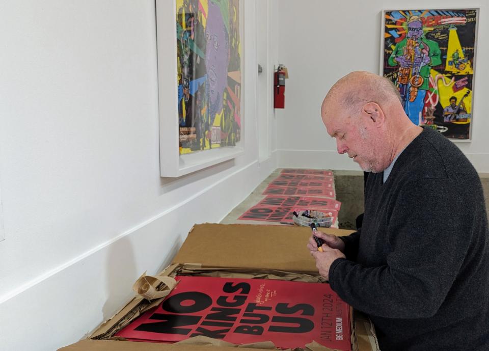 Tim Kerr signs posters before the "No Kings But Us" exhibit opens at Big Medium. Kerr and Hodge passed canvases back and forth for a year. They collaged images and augmented and painted over each other's work to create the pieces in the exhibition.