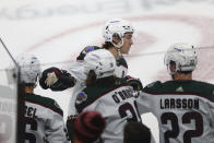 Arizona Coyotes right wing Clayton Keller, top, is congratulated by teammates on the bench after his goal against the Minnesota Wild during the first period of an NHL hockey game Tuesday, Nov. 30, 2021, in St. Paul, Minn. (AP Photo/Stacy Bengs)