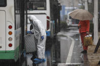 A worker wearing a protective suit helps a patient carry their luggage as they arrive at a tumor hospital newly designated to treat COVID-19 patients in Wuhan in central China's Hubei Province, Saturday, Feb. 15, 2020. The virus is thought to have infected more than 67,000 people globally and has killed at least 1,526 people, the vast majority in China, as the Chinese government announced new anti-disease measures while businesses reopen following sweeping controls that have idled much of the economy. (Chinatopix via AP)