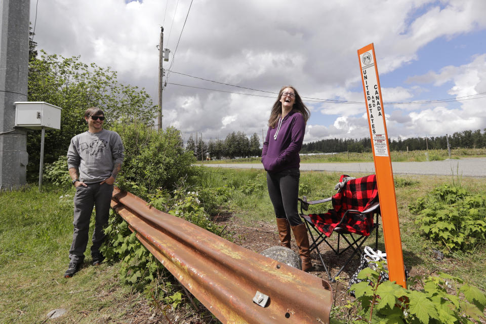 In this photo taken May 17, 2020, Kris Browning, right, laughs as she stands in Canada while visiting her husband, Tim Browning, in the U.S., near Lynden, Wash. With the border closed to nonessential travel amid the global pandemic, families and couples across the continent have found themselves cut off from loved ones on the other side. (AP Photo/Elaine Thompson)