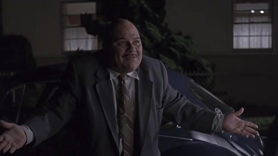 Jon Polito looking frustrated, wearing a suit, holding his arms back